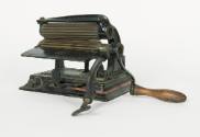 A cast iron fluting iron with a clamp, wooden handle and brass rollers.