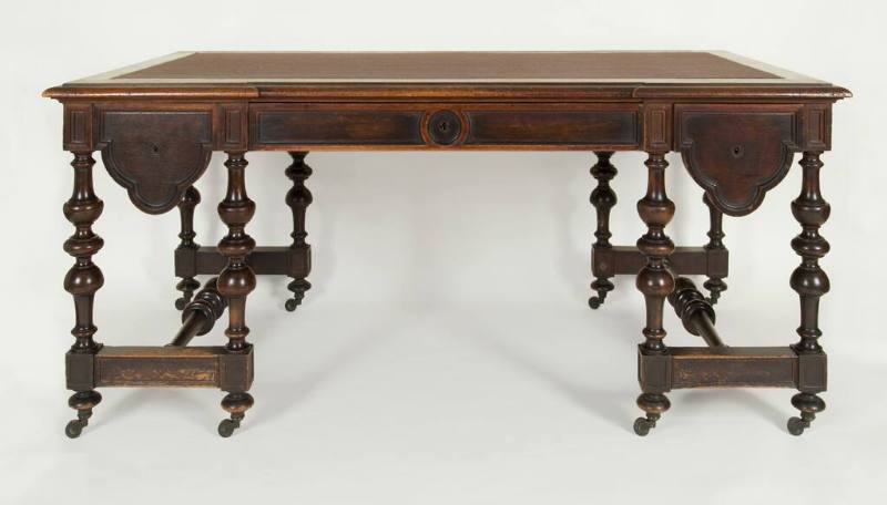A Victorian walnut library table with leather-paneled top and curved-molding drawer fronts bene…