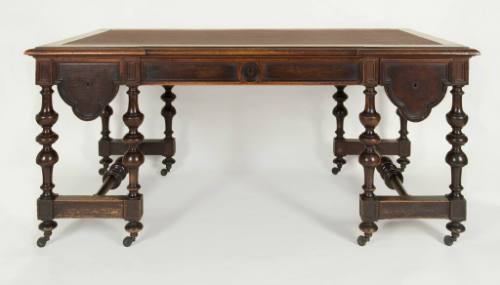 A Victorian walnut library table with leather-paneled top and curved-molding drawer fronts bene…